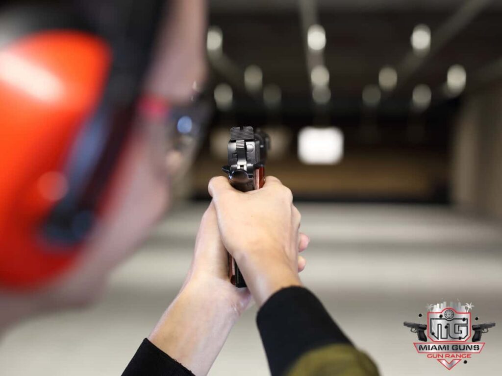 Person shooting handgun at gun range wearing ear protection - Best Gun Store And Range In Miami: Why Miami Guns Should Be Your First Stop